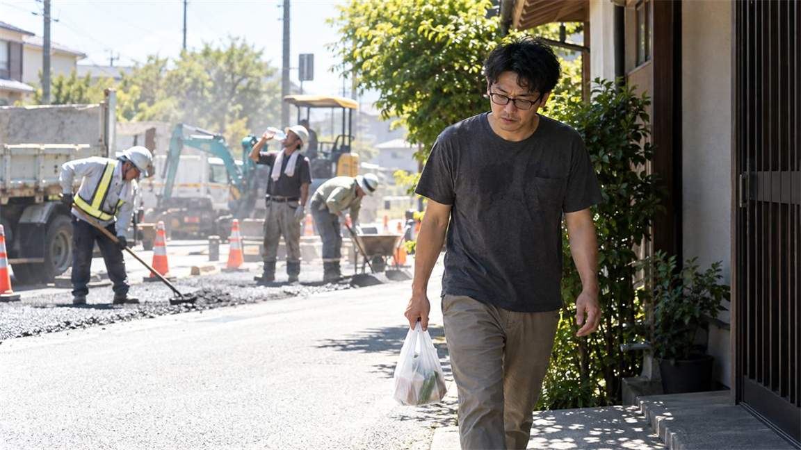 炎天下で働く人たちを横目に、買い物を終えて家へ向かう眼鏡の男性